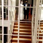 Bride and groom stand on the stairs in front of a mirror.