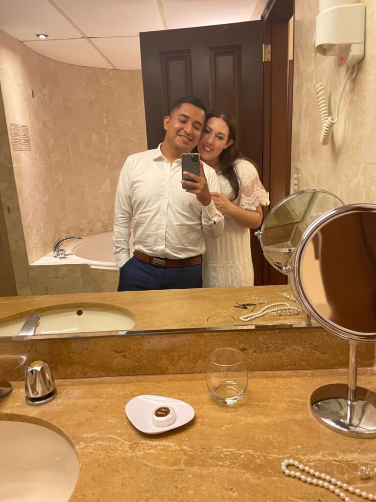 Bride and groom take a selfie in the bathroom mirror of their hotel room on their wedding night.